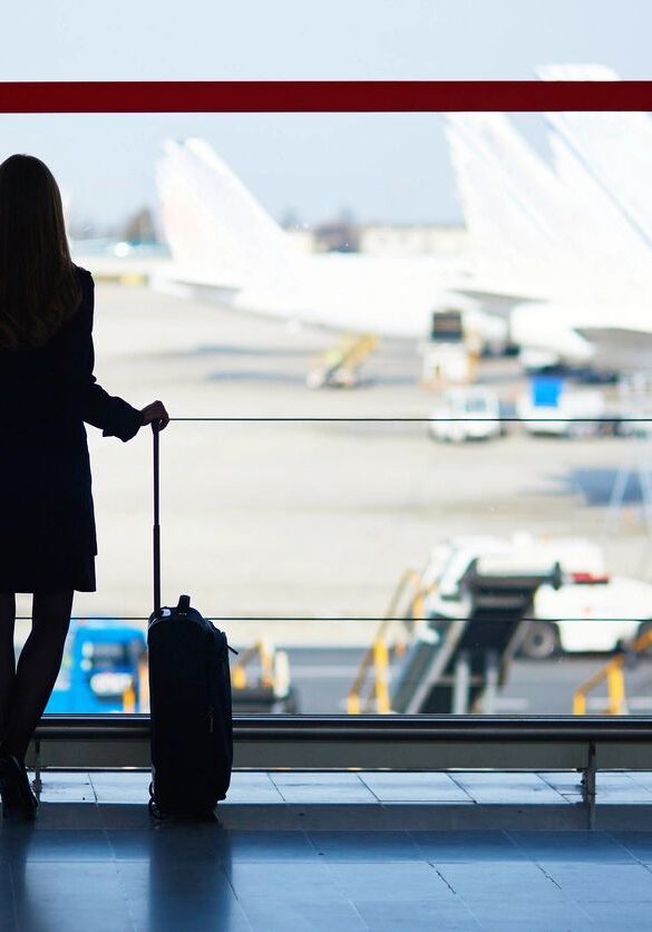 Young woman in the airport, looking through the window at planes